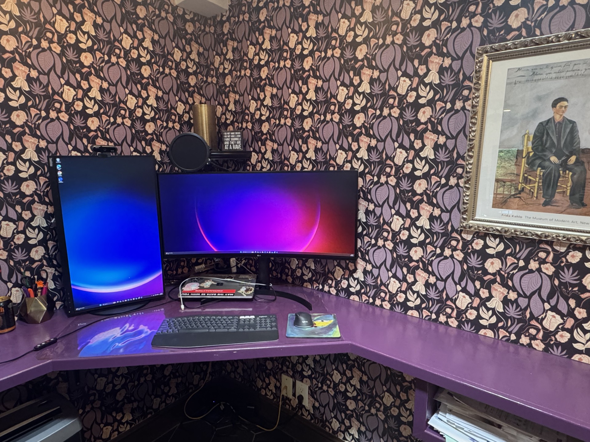 Tiffany Gonzalez's actual home-office desk in Austin, painted purple, with a dual-monitor setup and a Frida Kahlo print on the wall